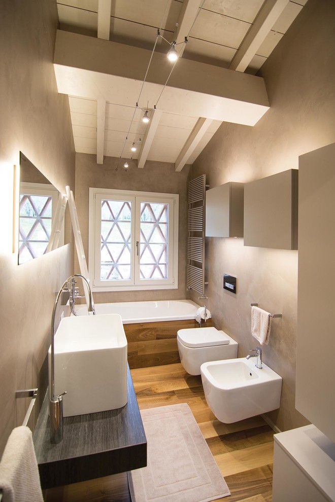 Foto på ett mellanstort funkis en-suite badrum, med släta luckor, beige skåp, ett platsbyggt badkar, en bidé, beige kakel, beige väggar, ljust trägolv, ett avlångt handfat och granitbänkskiva