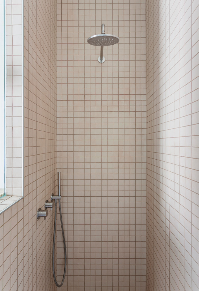 Idéer för mellanstora funkis brunt badrum med dusch, med släta luckor, skåp i ljust trä, en dusch i en alkov, en vägghängd toalettstol, orange kakel, cementkakel, vita väggar, betonggolv, ett fristående handfat, träbänkskiva, grått golv och dusch med gångjärnsdörr