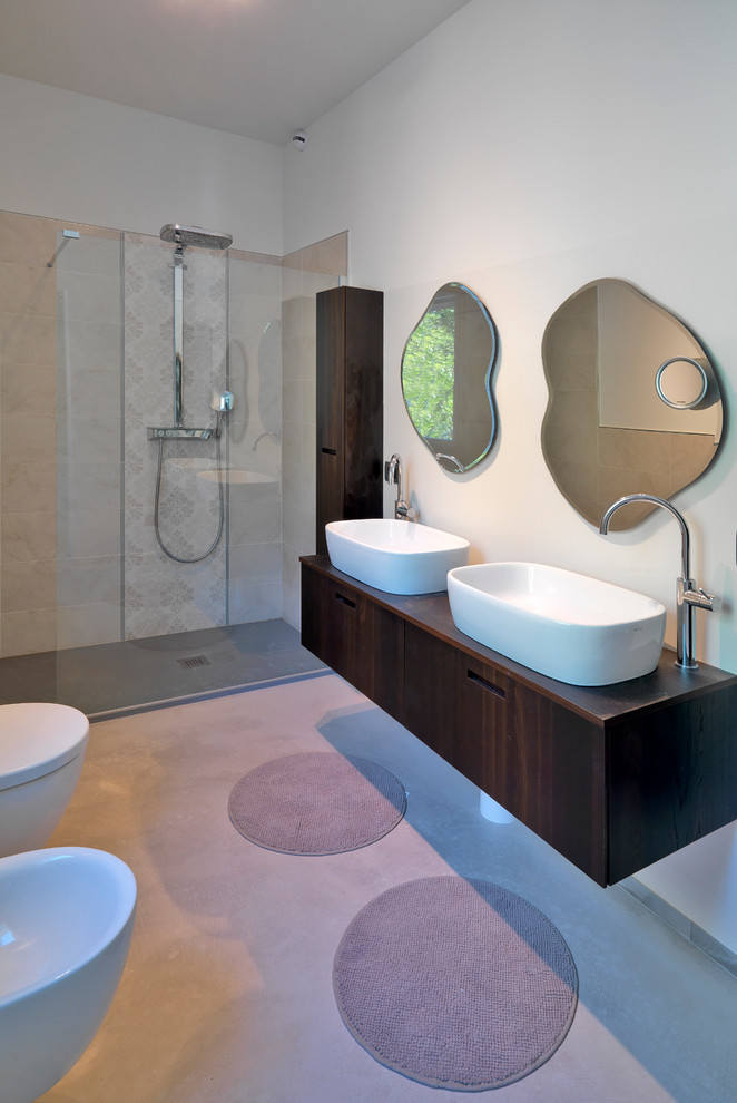 Стильный дизайн: ванная комната в современном стиле с плоскими фасадами, темными деревянными фасадами, душем без бортиков, инсталляцией, белыми стенами, бетонным полом, душевой кабиной, настольной раковиной, столешницей из дерева и открытым душем - последний тренд