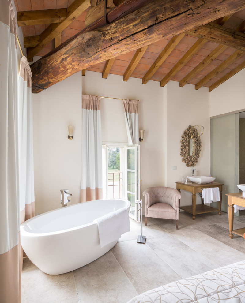 На фото: главная ванная комната в стиле кантри с открытыми фасадами, светлыми деревянными фасадами, отдельно стоящей ванной, белыми стенами, настольной раковиной и столешницей из дерева