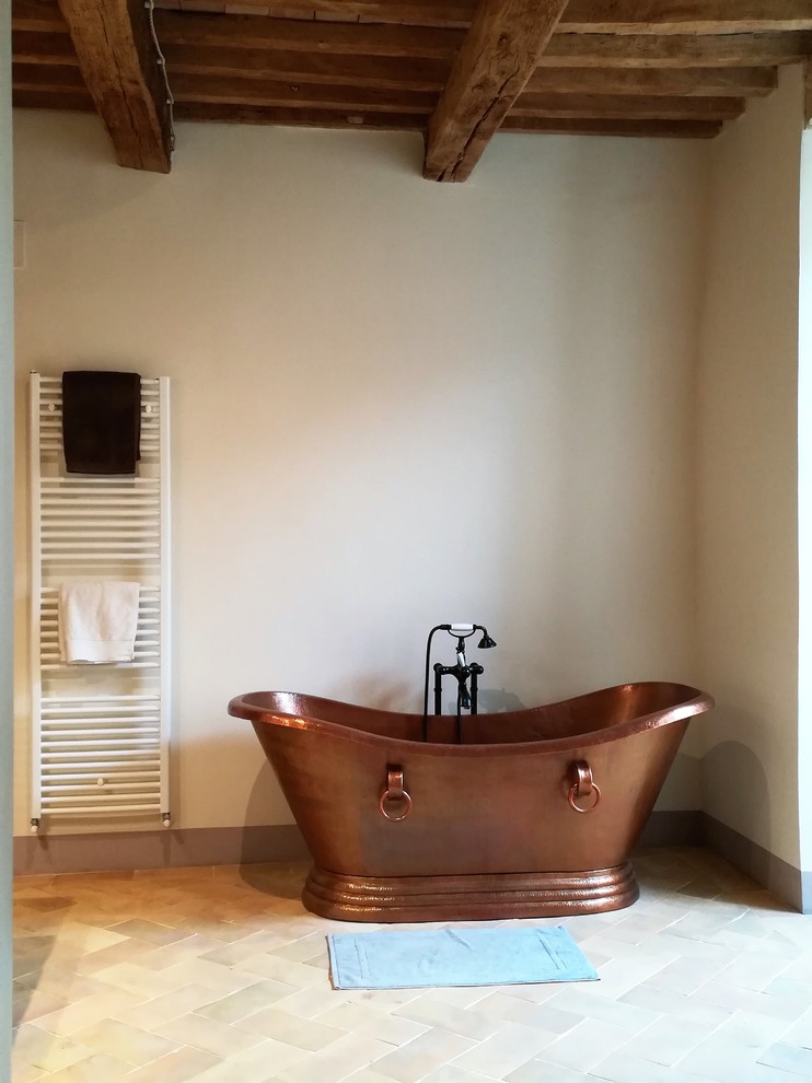 На фото: ванная комната в средиземноморском стиле с отдельно стоящей ванной, белыми стенами, полом из терракотовой плитки и бежевым полом с