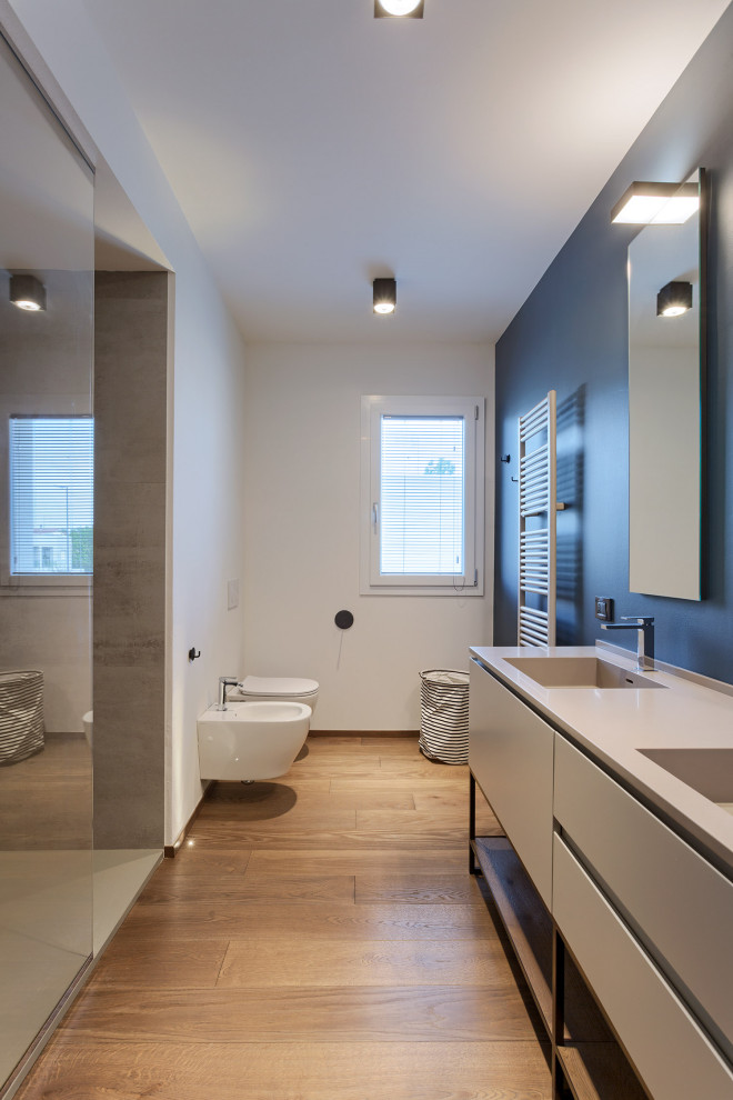 На фото: большая ванная комната в современном стиле с серыми фасадами, душем в нише, инсталляцией, белыми стенами, паркетным полом среднего тона, душевой кабиной, монолитной раковиной, бежевым полом, серой столешницей и плоскими фасадами