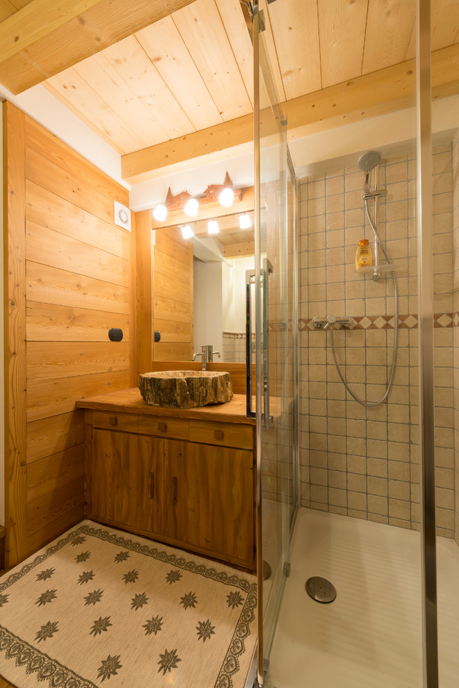 Réalisation d'une petite salle d'eau chalet en bois brun avec un placard à porte plane, une douche d'angle, un plan vasque et un plan de toilette en bois.
