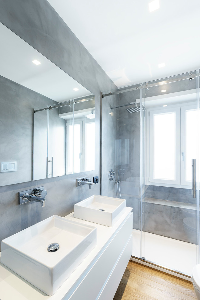 Diseño de cuarto de baño contemporáneo con armarios con paneles lisos, puertas de armario blancas, ducha empotrada, paredes grises, suelo de madera en tonos medios, aseo y ducha, lavabo sobreencimera y suelo marrón
