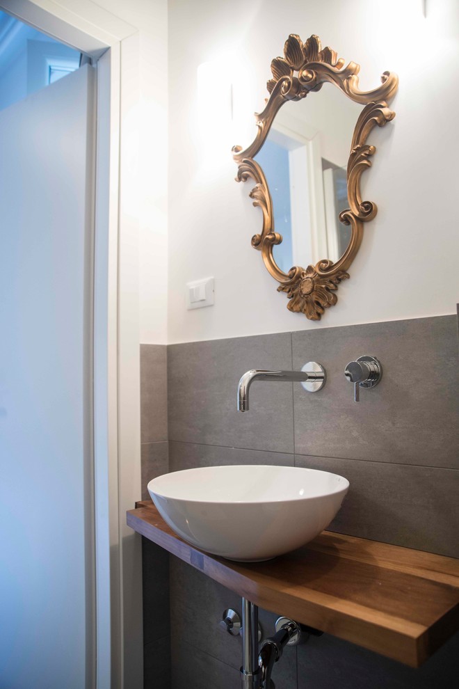 This is an example of a small eclectic shower room bathroom in Rome with a wall mounted toilet, grey tiles, porcelain tiles, white walls, porcelain flooring, a vessel sink, wooden worktops and grey floors.