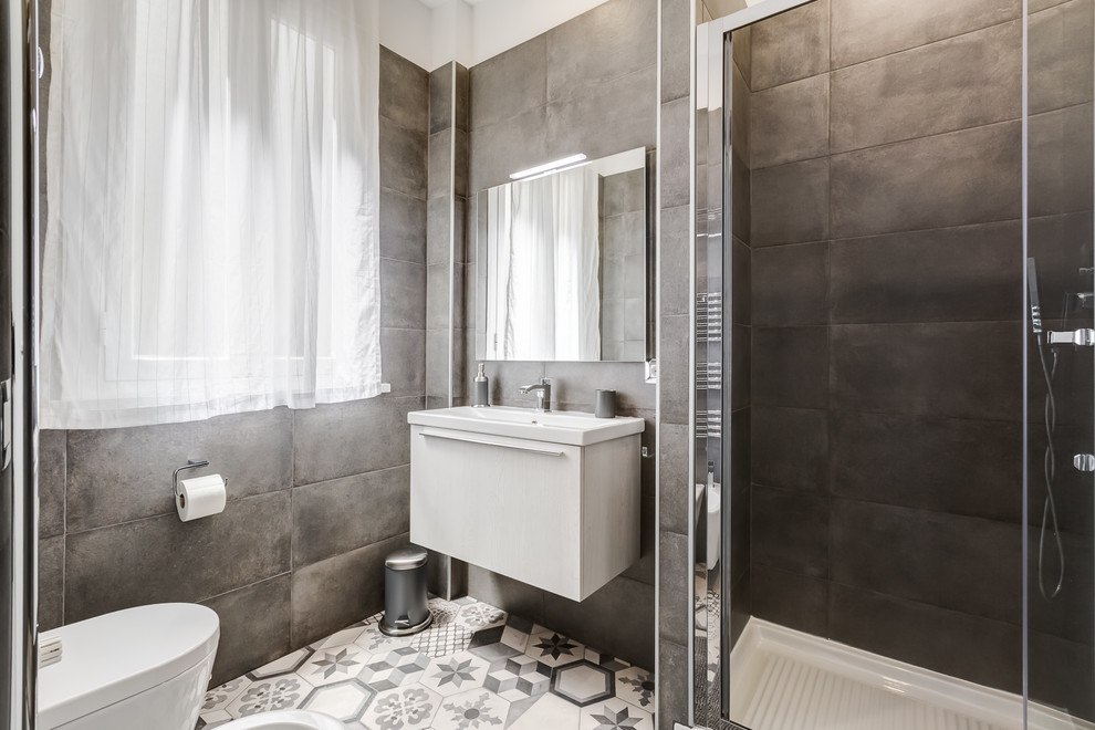 Small contemporary shower room bathroom in Rome with flat-panel cabinets, white cabinets, a corner shower, a wall mounted toilet, brown walls, ceramic flooring, a wall-mounted sink, multi-coloured floors and a sliding door.