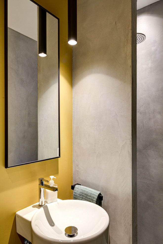 Exemple d'une petite salle d'eau tendance avec une douche à l'italienne, WC suspendus, un mur gris, sol en béton ciré, un lavabo suspendu, un sol gris et aucune cabine.