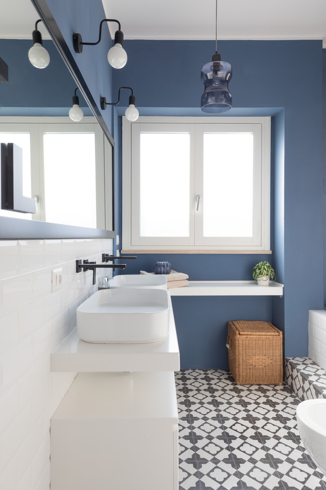 Идея дизайна: ванная комната в современном стиле с плоскими фасадами, белыми фасадами, биде, белой плиткой, плиткой кабанчик, синими стенами, настольной раковиной, разноцветным полом и белой столешницей