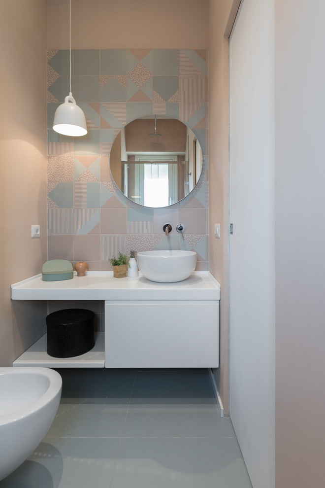 Réalisation d'une salle de bain design avec un placard à porte plane, des portes de placard blanches, un bidet, un carrelage vert, un carrelage rose, un mur rose, une vasque, un sol vert et un plan de toilette blanc.