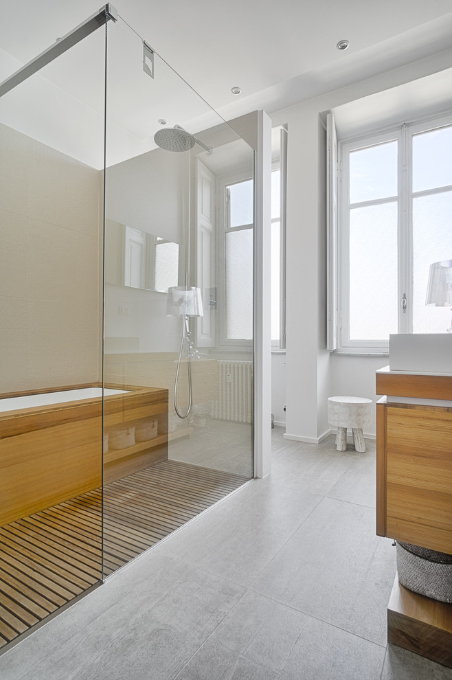 Modelo de cuarto de baño principal actual con puertas de armario de madera clara y combinación de ducha y bañera