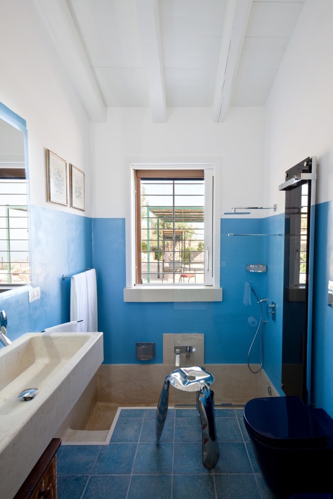 Cette image montre une salle de bain principale méditerranéenne avec une baignoire en alcôve, un combiné douche/baignoire, un mur bleu, une grande vasque et aucune cabine.