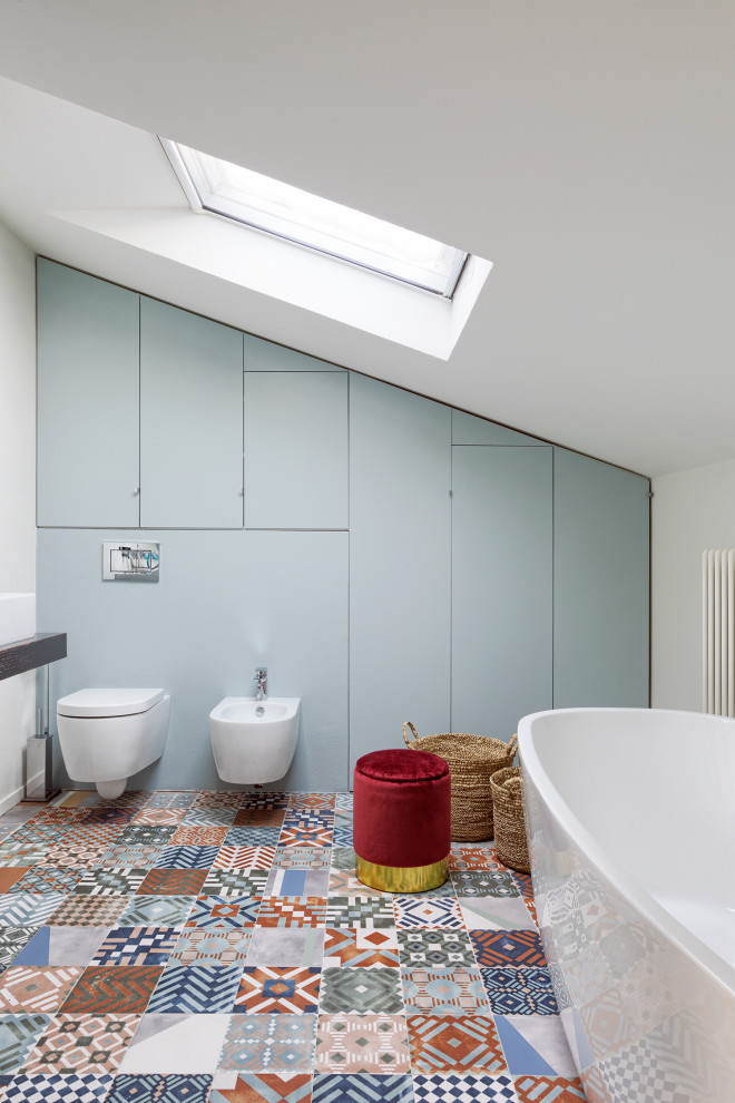 Exemple d'une salle de bain principale tendance de taille moyenne avec une baignoire indépendante, WC suspendus, un mur blanc, un sol en carrelage de terre cuite et un sol multicolore.