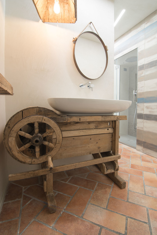 Diseño de cuarto de baño industrial pequeño con puertas de armario de madera clara, ducha esquinera, sanitario de dos piezas, paredes grises, suelo de baldosas de terracota, aseo y ducha, lavabo integrado y encimera de madera