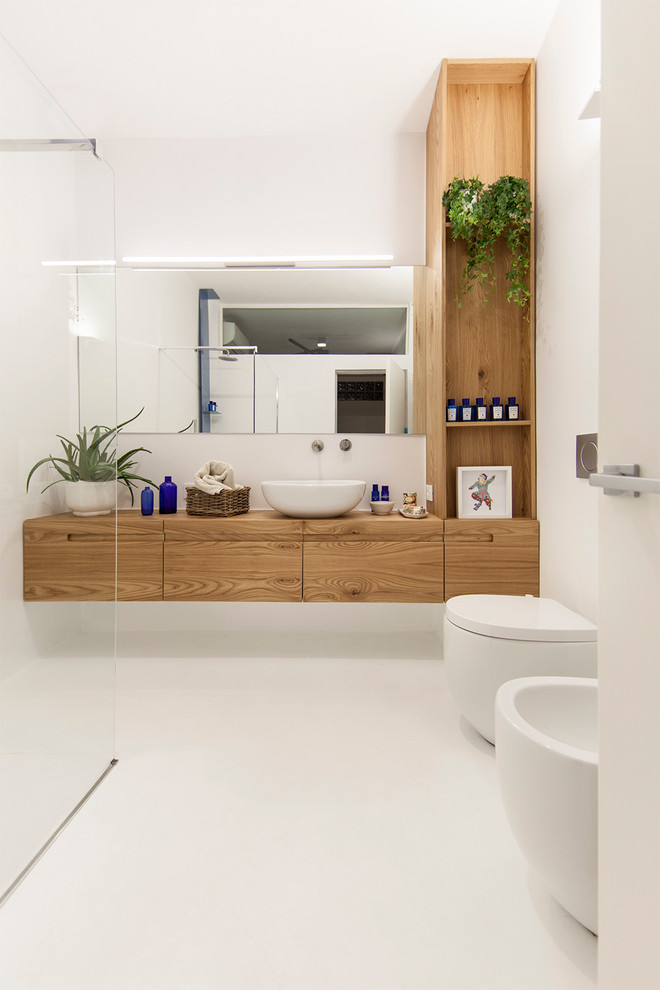 Exempel på ett mellanstort modernt brun brunt badrum med dusch, med släta luckor, skåp i ljust trä, en kantlös dusch, vita väggar, ett fristående handfat, träbänkskiva, en toalettstol med hel cisternkåpa och med dusch som är öppen