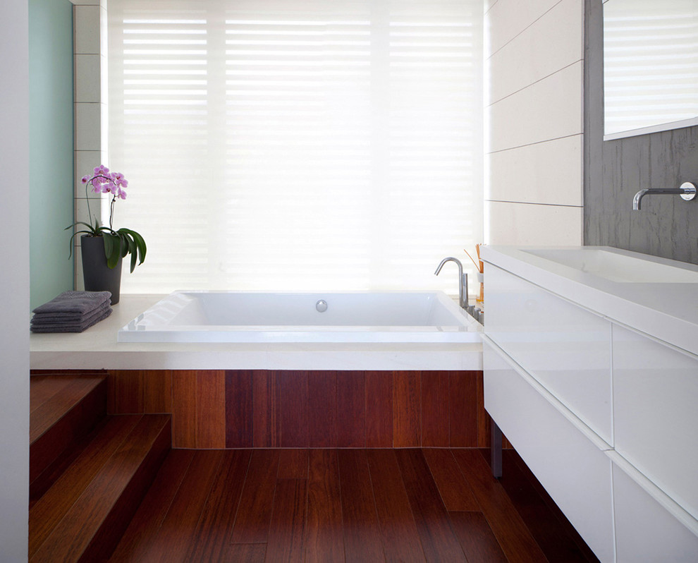 Exempel på ett modernt en-suite badrum, med släta luckor, vita skåp, ett platsbyggt badkar, vit kakel, mörkt trägolv och ett integrerad handfat