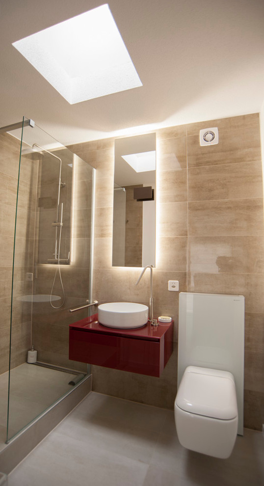 Bild på ett litet funkis badrum med dusch, med röda skåp, en kantlös dusch, en toalettstol med hel cisternkåpa, beige kakel, porslinskakel, vita väggar, klinkergolv i porslin, ett fristående handfat och bänkskiva i glas