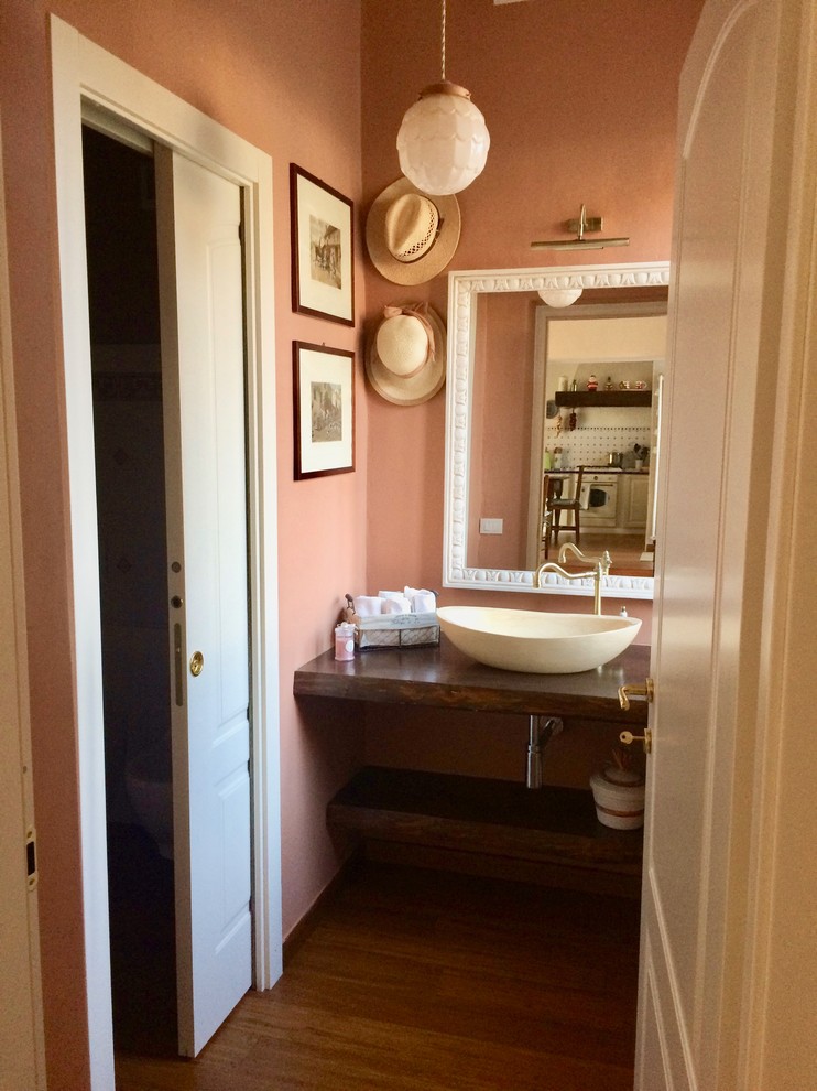 Idée de décoration pour une grande salle d'eau champêtre avec un placard sans porte, des portes de placard marrons, WC séparés, un mur rose, parquet en bambou, une vasque, un plan de toilette en bois, un sol marron et un plan de toilette marron.