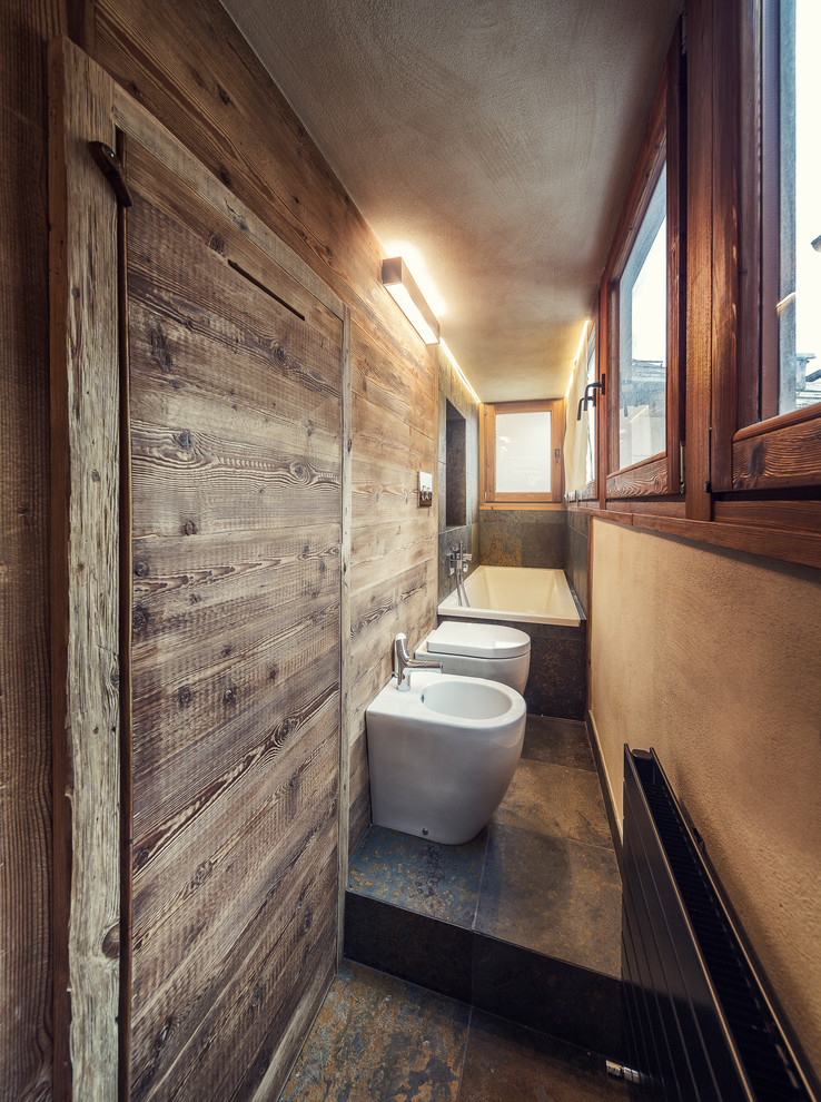 На фото: главная ванная комната среднего размера в стиле рустика с ванной в нише, душем над ванной, биде, бежевыми стенами и открытым душем
