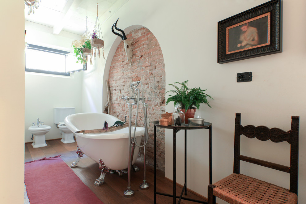 Modelo de cuarto de baño principal mediterráneo con bañera con patas, sanitario de dos piezas, ducha empotrada, paredes beige, suelo de madera oscura y suelo marrón