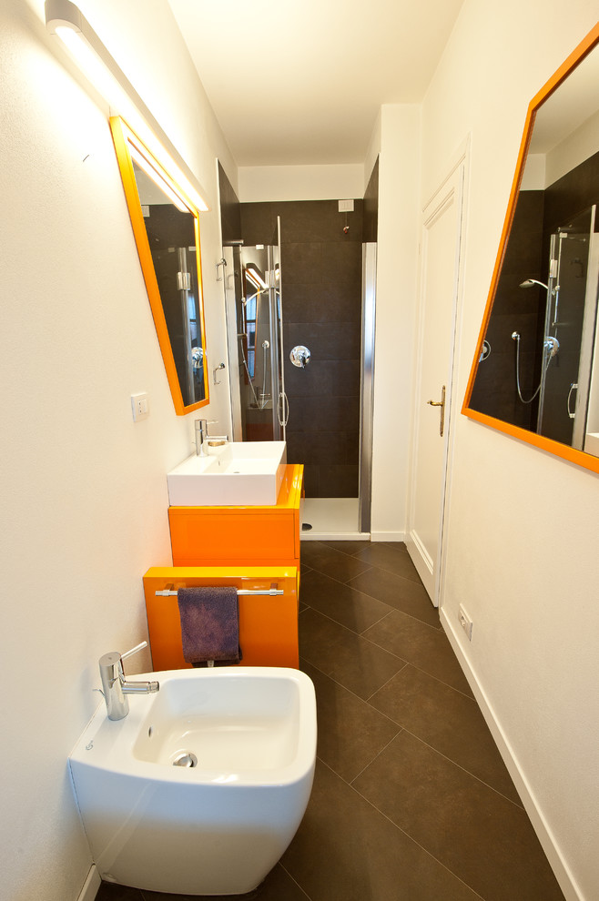 Modern inredning av ett litet badrum med dusch, med orange skåp, ett platsbyggt badkar, en dusch i en alkov, en toalettstol med separat cisternkåpa, brun kakel, porslinskakel, vita väggar, klinkergolv i porslin, ett fristående handfat och träbänkskiva