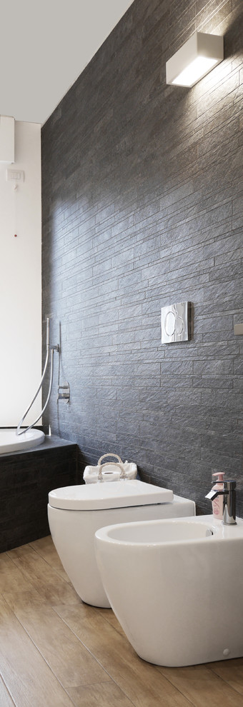 Kleines Modernes Badezimmer En Suite mit offenen Schränken, schwarzen Schränken, Eckbadewanne, Duschbadewanne, Bidet, grauen Fliesen, weißer Wandfarbe, hellem Holzboden, Aufsatzwaschbecken, braunem Boden und offener Dusche in Mailand