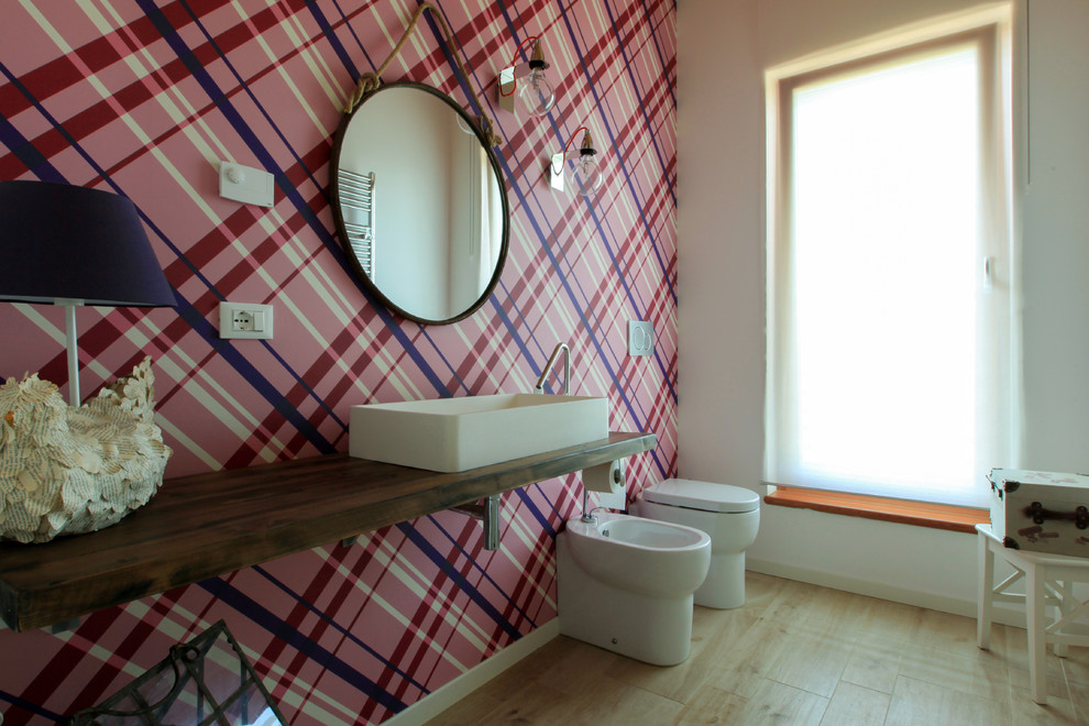 Diseño de cuarto de baño moderno de tamaño medio con bidé, paredes rosas, suelo de madera en tonos medios, lavabo sobreencimera, encimera de madera y suelo beige