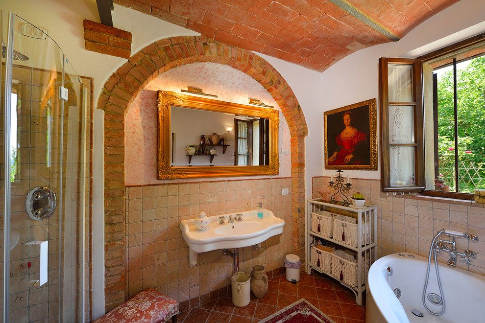 Immagine di una stanza da bagno mediterranea con vasca freestanding, piastrelle in terracotta, pareti bianche e lavabo sospeso