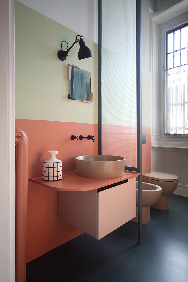 ミラノにある中くらいなエクレクティックスタイルのおしゃれな浴室 (オレンジのタイル、ベッセル式洗面器、黒い床、フラットパネル扉のキャビネット、一体型トイレ	、マルチカラーの壁、コンクリートの床) の写真