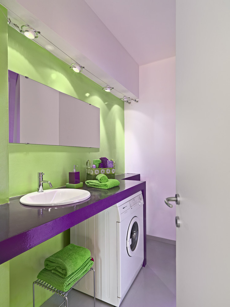 Modelo de cuarto de baño actual con puertas de armario violetas, paredes verdes, aseo y ducha, lavabo encastrado, suelo gris y encimeras moradas