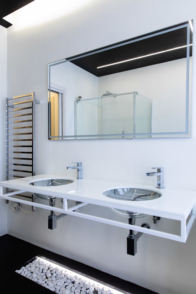 Diseño de cuarto de baño moderno con paredes blancas, lavabo bajoencimera, suelo negro y encimeras blancas