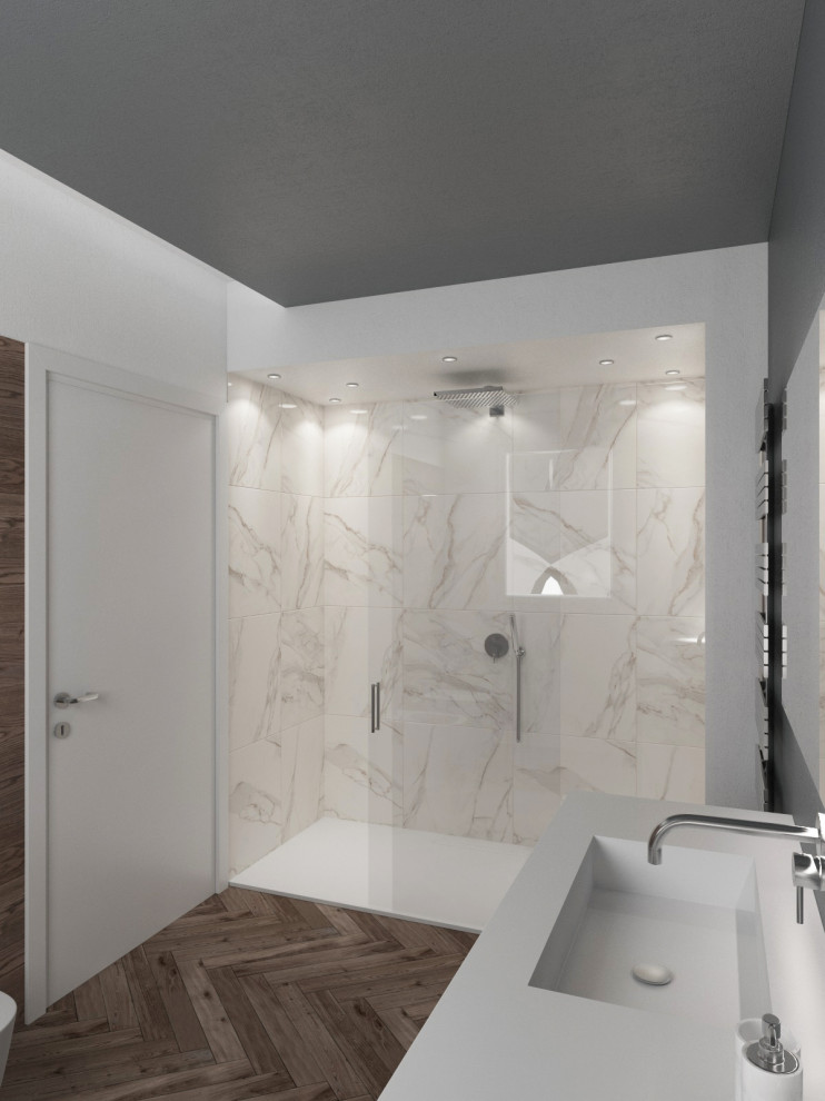Bild på ett mellanstort funkis vit vitt badrum med dusch, med släta luckor, vita skåp, en toalettstol med separat cisternkåpa, vit kakel, porslinskakel, grå väggar, mörkt trägolv, ett integrerad handfat, bänkskiva i akrylsten, brunt golv, en kantlös dusch och dusch med skjutdörr