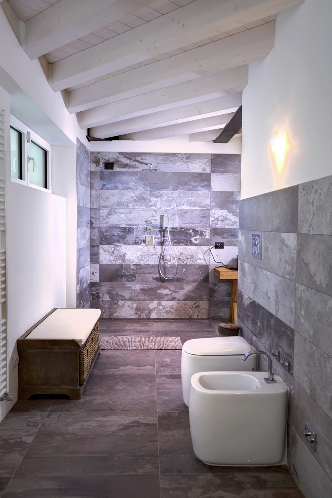 Klassisk inredning av ett badrum, med grå kakel, stenhäll, vita väggar och en kantlös dusch