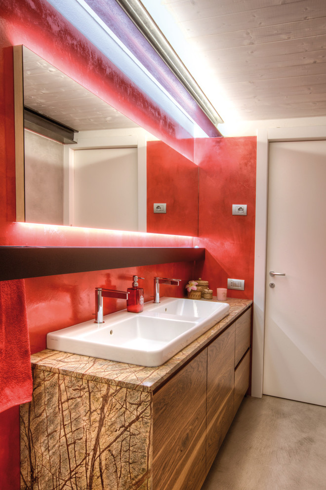 Aménagement d'une salle de bain industrielle en bois clair de taille moyenne avec un placard à porte plane, une douche à l'italienne, WC suspendus, un mur rouge, un lavabo posé, un plan de toilette en marbre et une cabine de douche à porte coulissante.