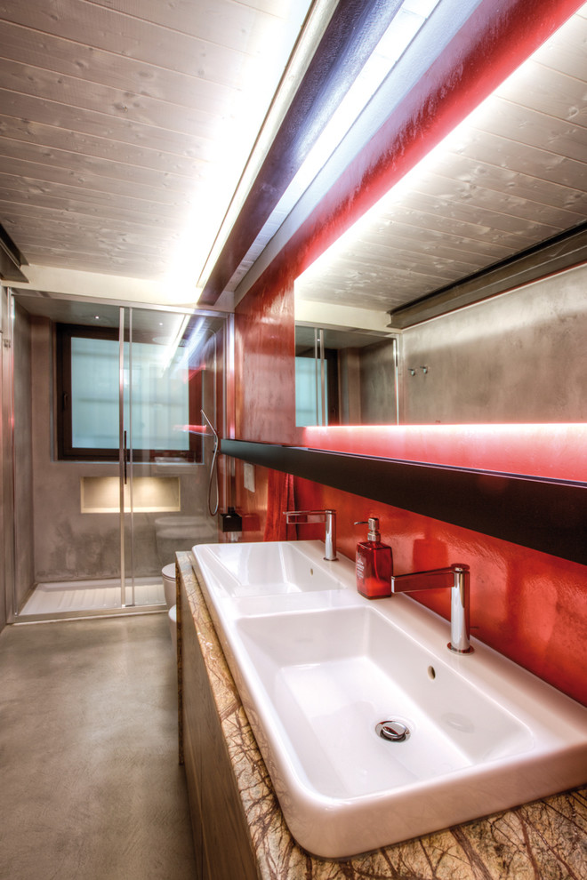 Cette photo montre une salle de bain industrielle en bois clair de taille moyenne avec un placard à porte plane, une douche à l'italienne, WC suspendus, un mur rouge, un lavabo posé, un plan de toilette en marbre et une cabine de douche à porte coulissante.