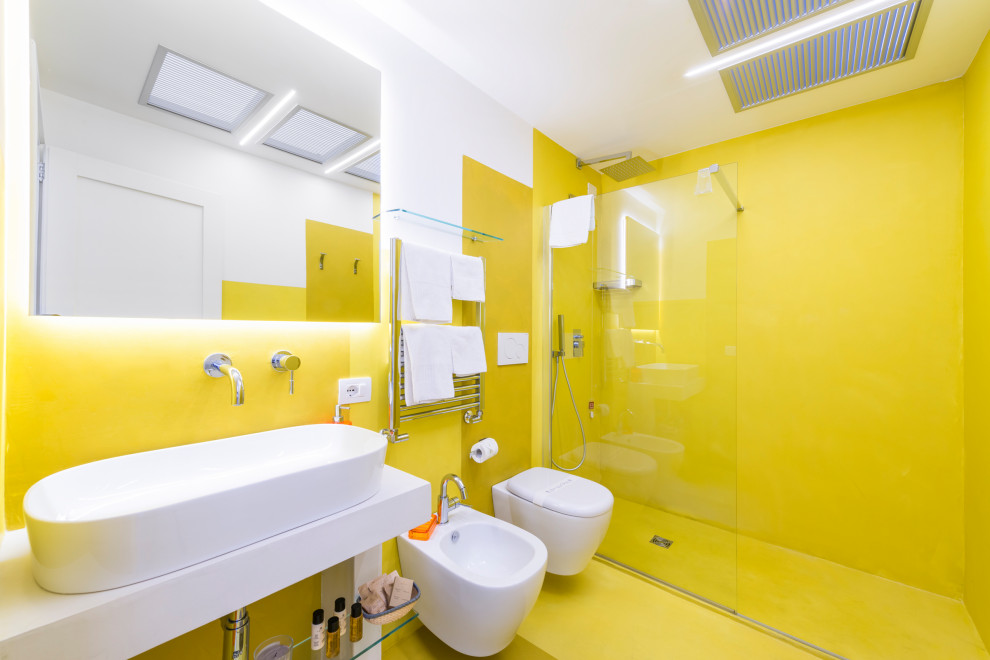 Пример оригинального дизайна: ванная комната среднего размера в современном стиле с белыми фасадами, душем без бортиков, инсталляцией, желтыми стенами, бетонным полом, душевой кабиной, столешницей из бетона, желтым полом, открытым душем, белой столешницей, тумбой под одну раковину, подвесной тумбой, многоуровневым потолком, открытыми фасадами и настольной раковиной