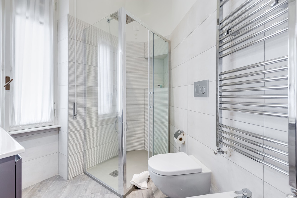 Immagine di una stanza da bagno con doccia design con ante grigie, doccia ad angolo, WC sospeso, pareti bianche, pavimento grigio, porta doccia a battente e top bianco