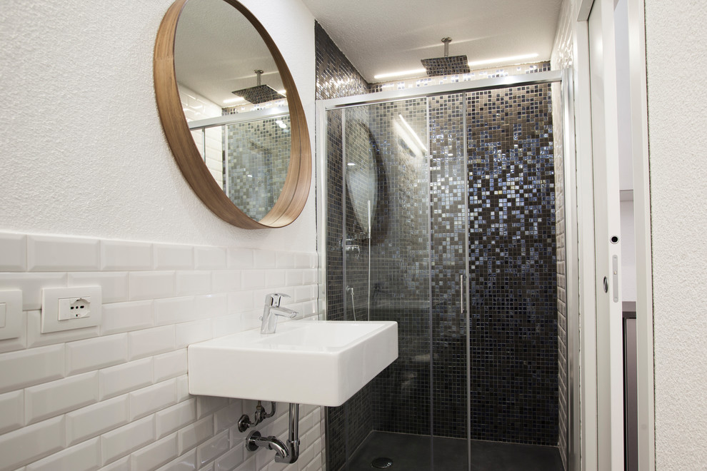 Bild på ett mellanstort industriellt badrum med dusch, med en dusch i en alkov, en toalettstol med separat cisternkåpa, vit kakel, keramikplattor, vita väggar, klinkergolv i porslin, ett väggmonterat handfat, svart golv och dusch med skjutdörr