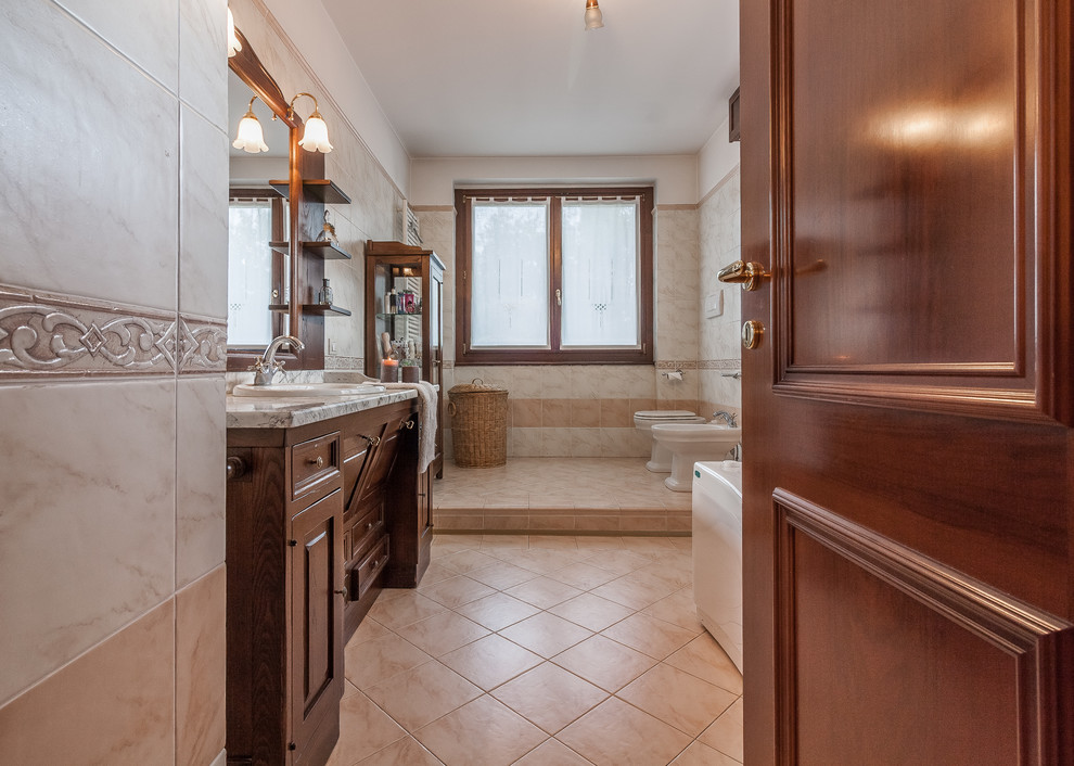 Foto på ett medelhavsstil badrum med dusch, med luckor med upphöjd panel, skåp i mörkt trä, en bidé, beige väggar, beiget golv och ett nedsänkt handfat