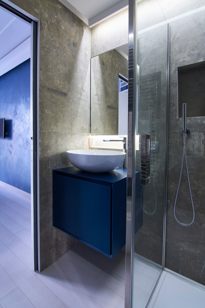 Идея дизайна: маленькая ванная комната в современном стиле с плоскими фасадами, синими фасадами, угловым душем, серой плиткой, душевой кабиной, настольной раковиной, серым полом, душем с распашными дверями, синей столешницей, нишей, тумбой под одну раковину и подвесной тумбой для на участке и в саду