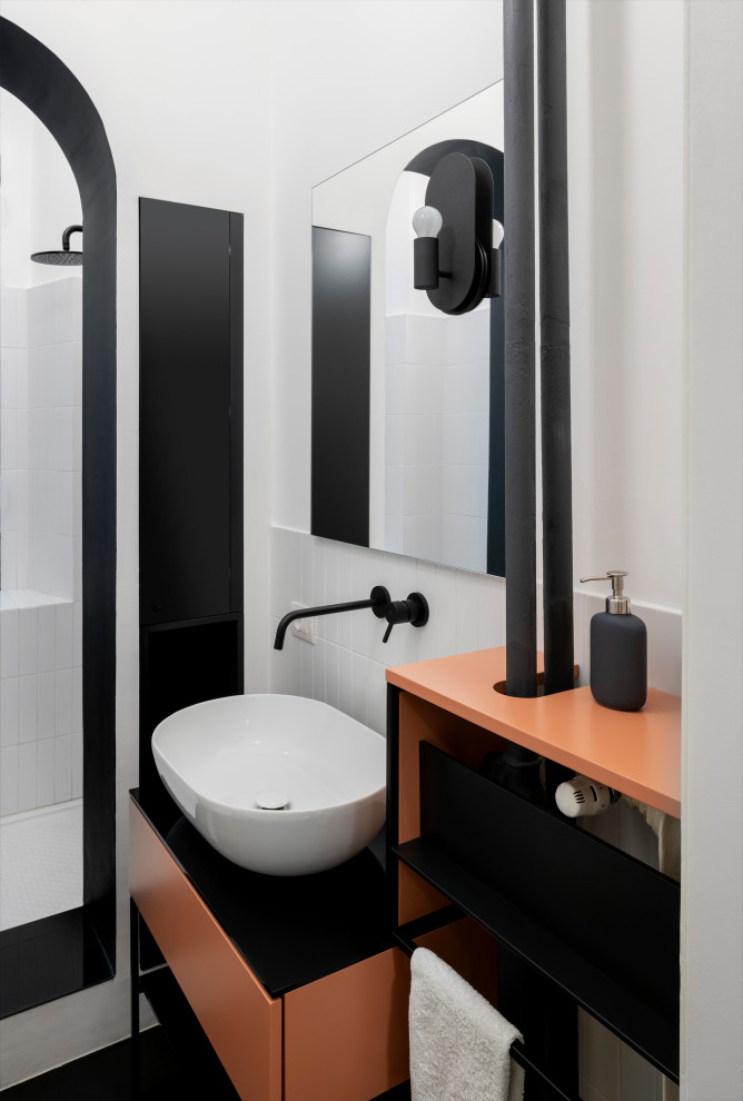 ミラノにある高級な中くらいな北欧スタイルのおしゃれなバスルーム (浴槽なし) (シェーカースタイル扉のキャビネット、オープン型シャワー、壁掛け式トイレ、白いタイル、セラミックタイル、白い壁、磁器タイルの床、ベッセル式洗面器、ガラスの洗面台、黒い床、オープンシャワー、黒い洗面カウンター、ニッチ、洗面台1つ、独立型洗面台) の写真
