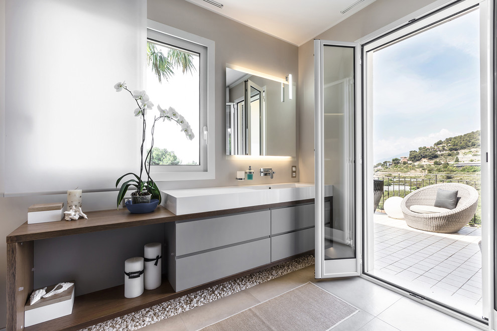 Imagen de cuarto de baño principal contemporáneo con armarios con paneles lisos, puertas de armario grises, paredes grises, encimera de madera, suelo gris y encimeras marrones