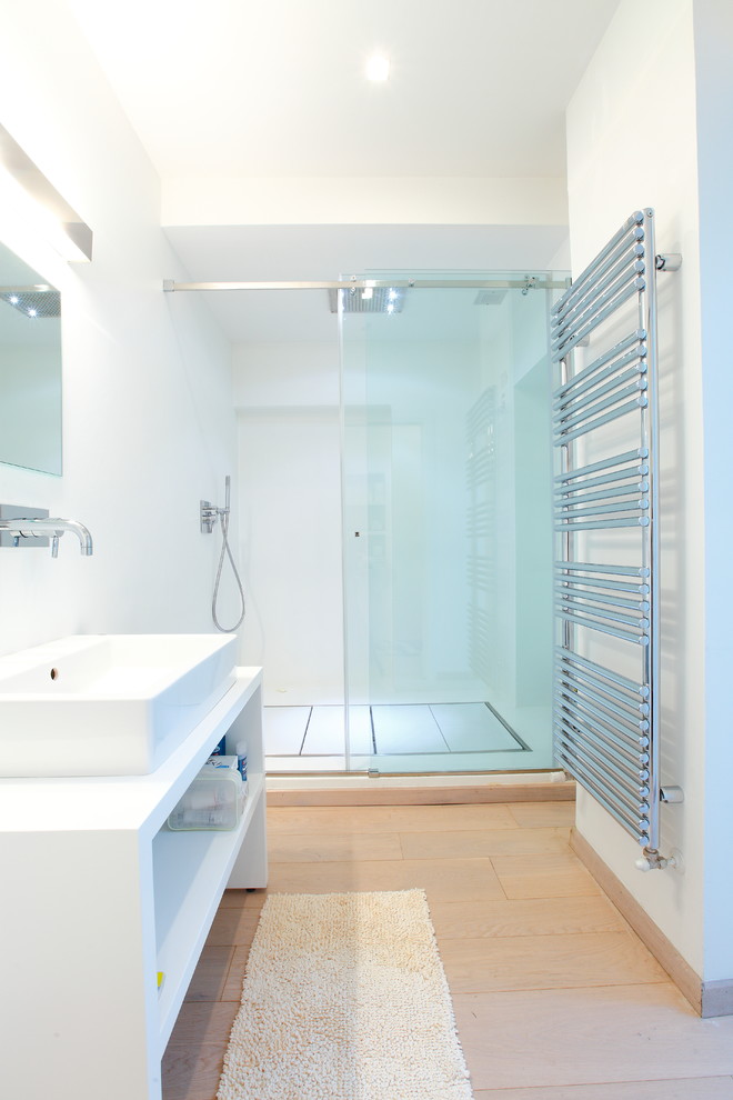 Medium sized modern shower room bathroom in Milan with white walls, light hardwood flooring, white cabinets, an alcove shower, a vessel sink, laminate worktops, a sliding door and open cabinets.