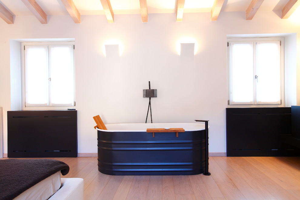 Стильный дизайн: главная ванная комната среднего размера в современном стиле с отдельно стоящей ванной, белыми стенами и светлым паркетным полом - последний тренд