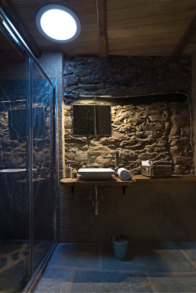 Пример оригинального дизайна: маленькая ванная комната в стиле рустика с искусственно-состаренными фасадами, двойным душем, плиткой из листового камня, разноцветными стенами, полом из сланца, душевой кабиной, настольной раковиной, столешницей из дерева, серым полом и коричневой столешницей для на участке и в саду