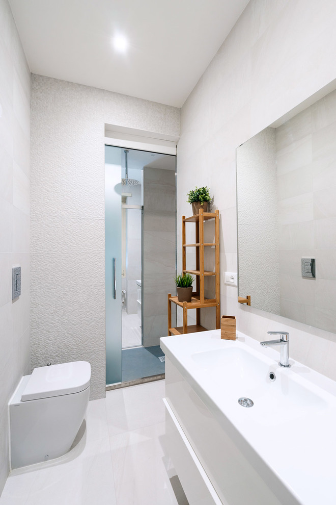 Источник вдохновения для домашнего уюта: маленькая ванная комната в современном стиле с плоскими фасадами, белыми фасадами, душем в нише, унитазом-моноблоком, белыми стенами, душевой кабиной, монолитной раковиной и душем с раздвижными дверями для на участке и в саду