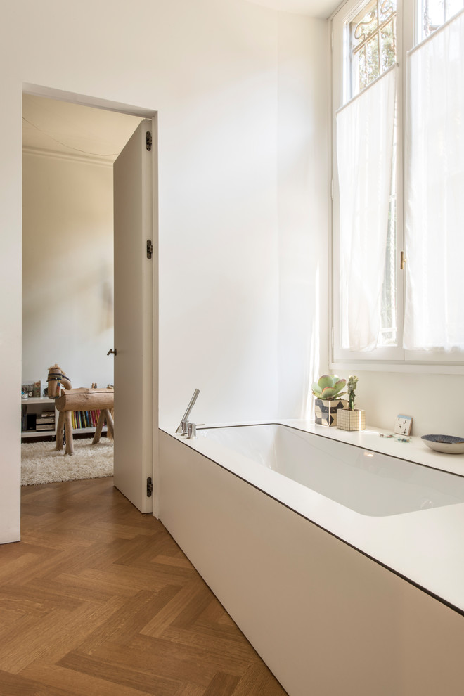Kleines Skandinavisches Badezimmer En Suite mit braunem Holzboden, Laminat-Waschtisch, weißer Waschtischplatte, Unterbauwanne, weißer Wandfarbe und braunem Boden in Mailand