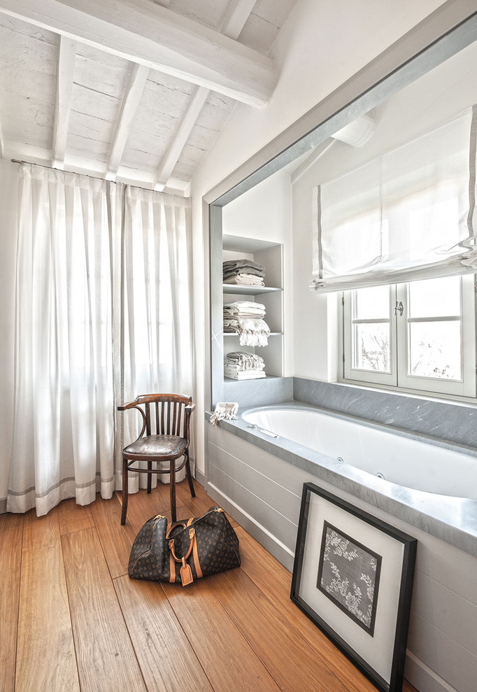 Immagine di una stanza da bagno padronale mediterranea con vasca sottopiano, pareti bianche e pavimento in legno massello medio