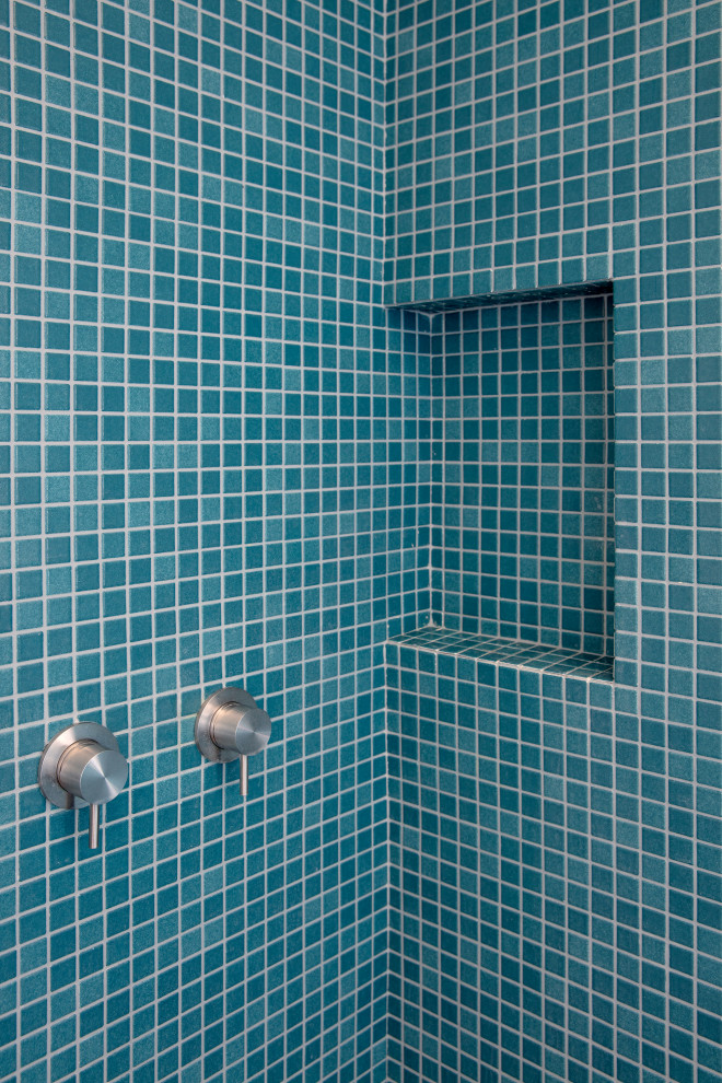 Ispirazione per una grande stanza da bagno con doccia design con ante a filo, ante in legno chiaro, piastrelle blu, piastrelle a mosaico e porta doccia scorrevole