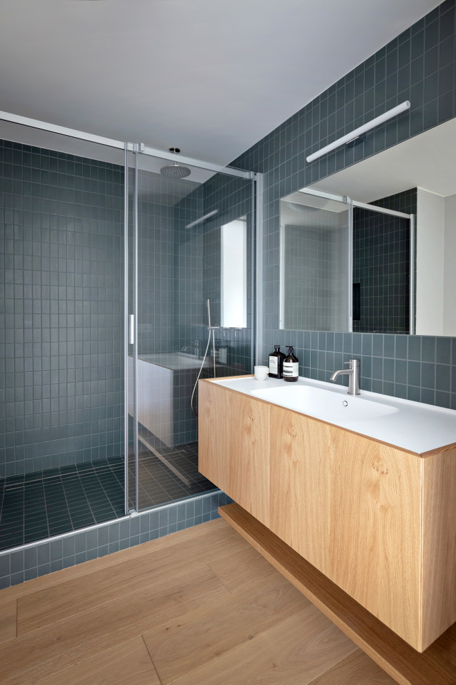 Diseño de cuarto de baño actual grande con aseo y ducha, puertas de armario de madera clara, suelo de madera clara, lavabo integrado y ducha con puerta corredera