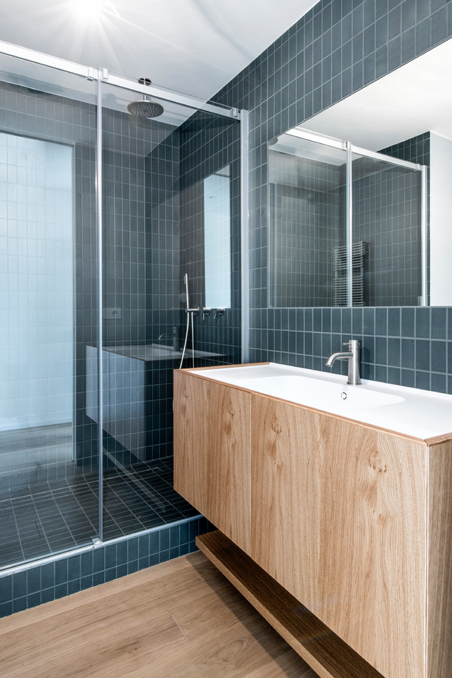 Imagen de cuarto de baño moderno con puertas de armario de madera oscura, suelo de madera en tonos medios, encimeras blancas y armarios con paneles lisos